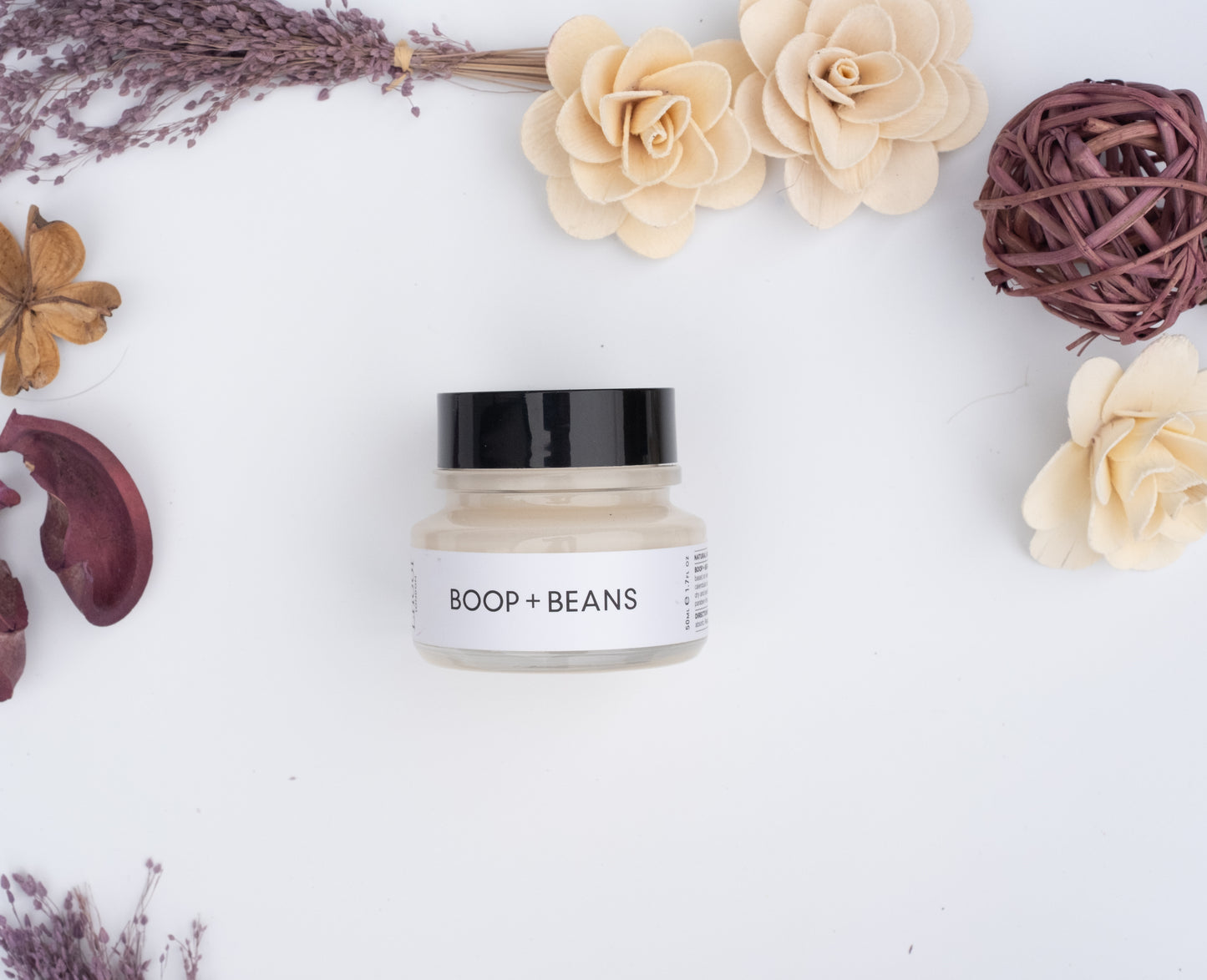 Jar of cream labeled 'Boop + Beans' on a white background with decorative flowers and elements.